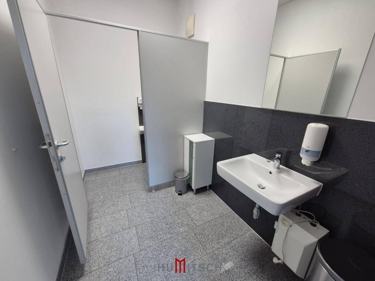 Moderne Toilette mit Waschbecken, Spiegel und Granitboden, sauber und gut gepflegt.