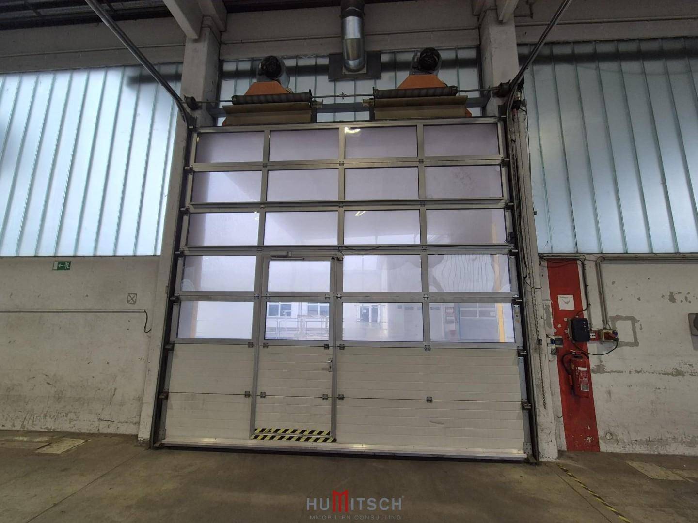 Großes Sektionaltor mit integrierten Fenstern im Innenbereich einer Lagerhalle, bereit für den Warenverkehr.