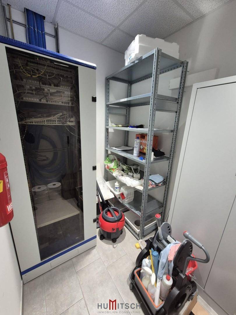 Serverraum mit Netzwerkschränken, Metallregalen und einem Feuerlöscher für die Sicherheit.