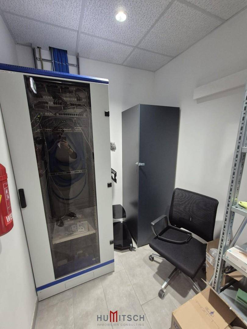 Serverraum mit Netzwerkschränken, einem schwarzen Schrank und einem Bürostuhl.