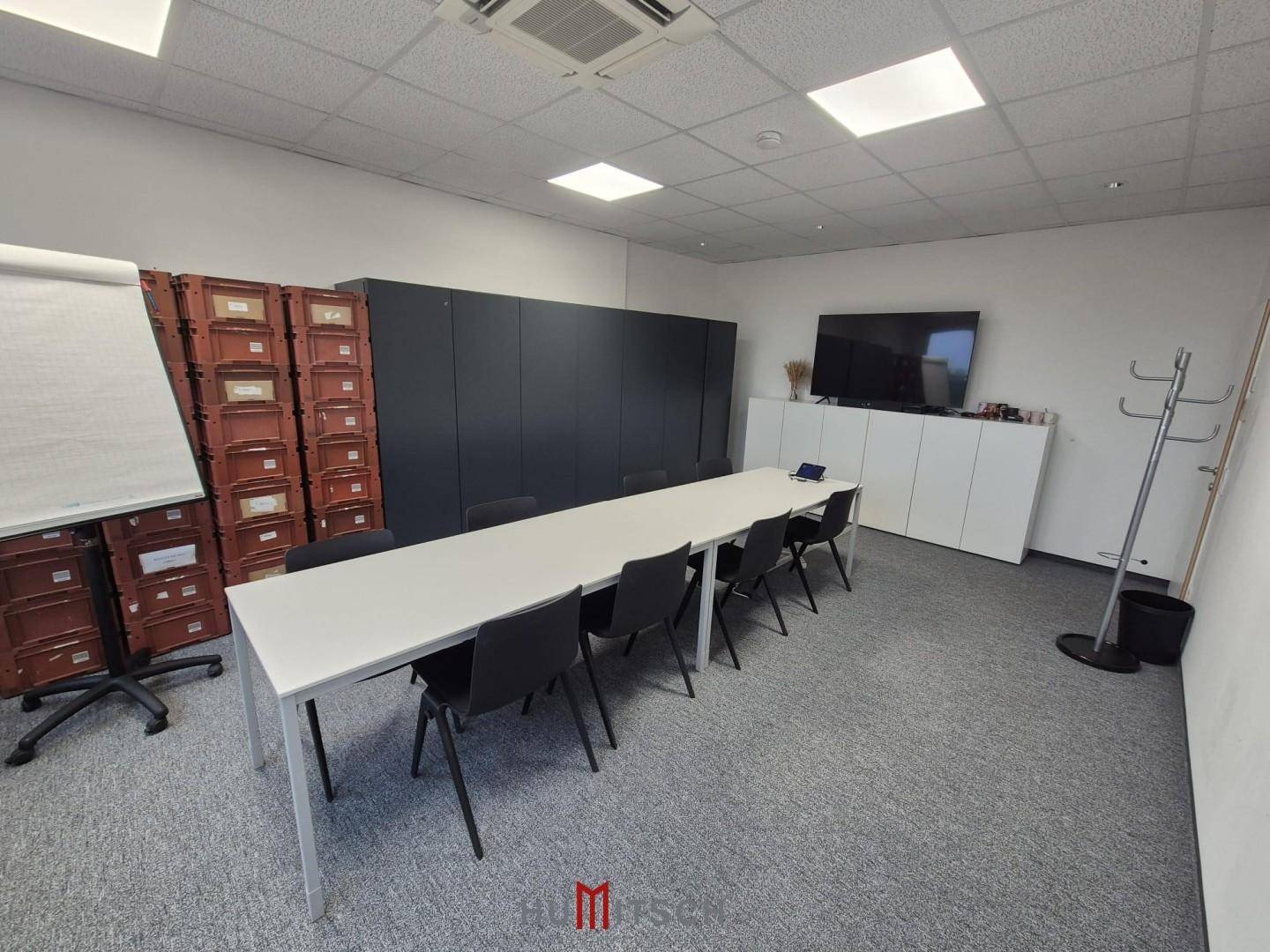 Geräumiger Konferenzraum mit langem Tisch, Stühlen, Whiteboard und Fernseher für Besprechungen.