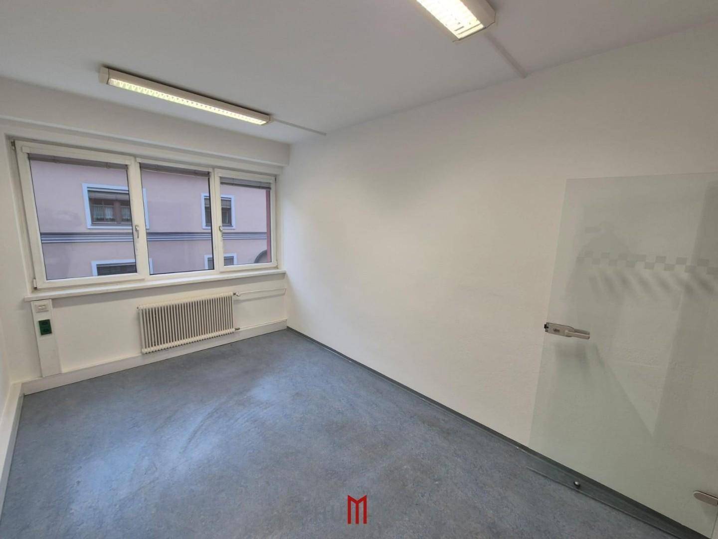 Kompaktes Büro mit Fenster und einer modernen Glastür, ideal für Einzelarbeitsplätze.