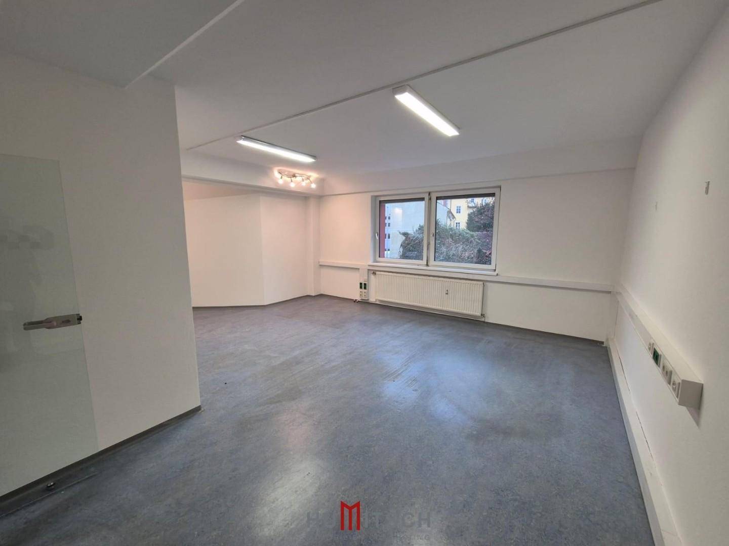 Leeres Büro mit Fenstern, die einen Blick nach draußen bieten, und praktischem Vinylboden.