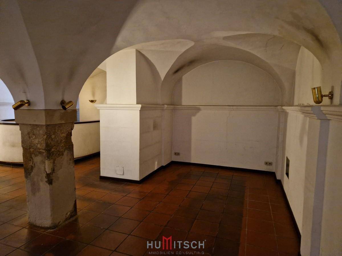 Tiefer Gewölbekeller mit markanten Steinsäulen und traditionellem Terrakottaboden, bietet eine einzigartige Atmosphäre.