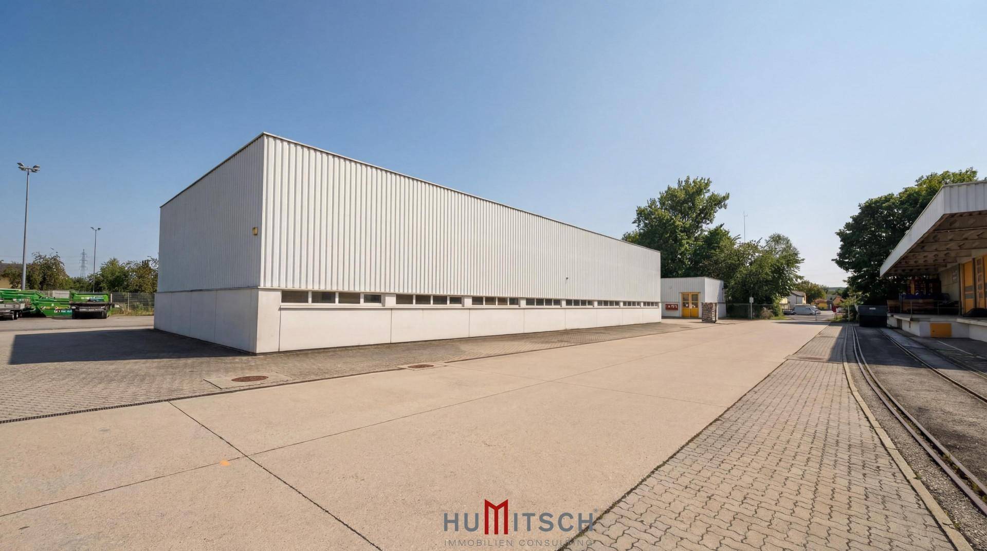 Langes Industriegebäude mit heller Fassade und zahlreichen Fenstern entlang der Seite.