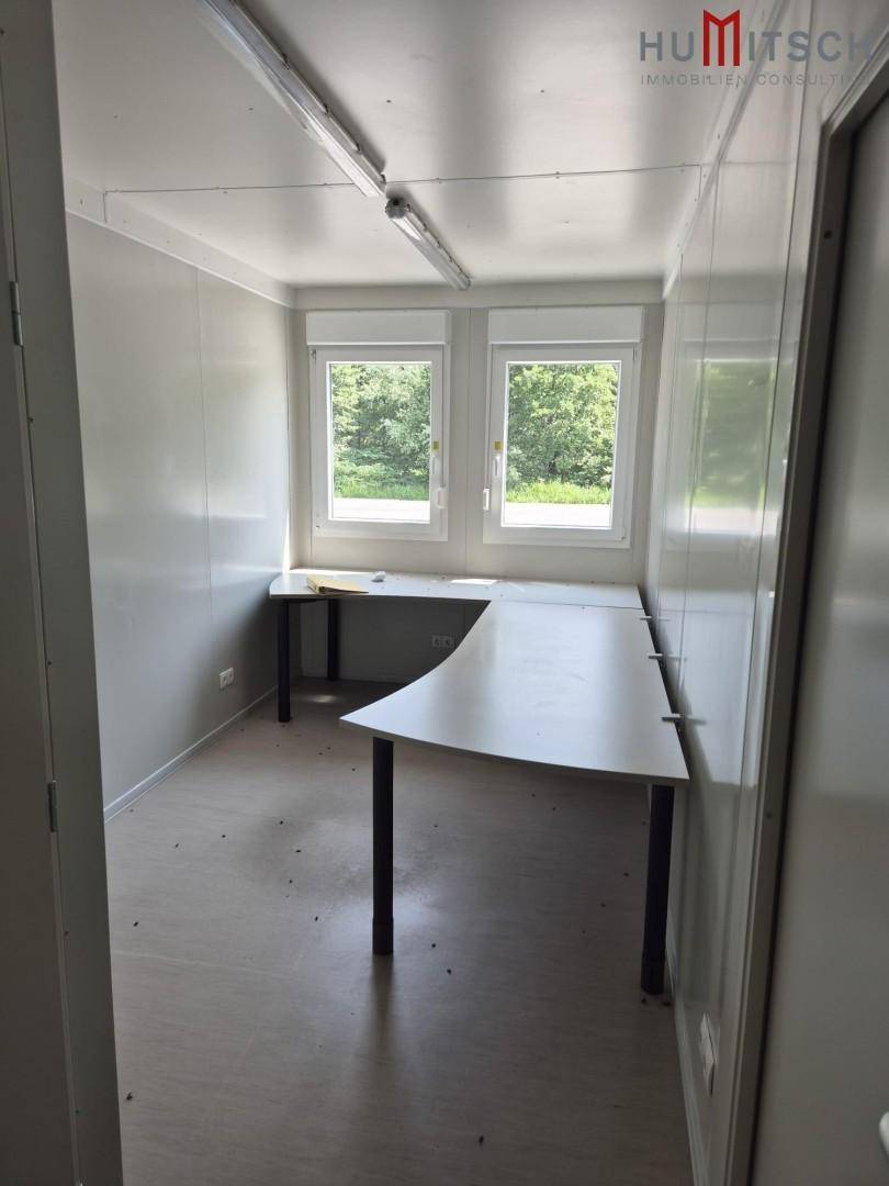 Kleines, helles Büro mit zwei Fenstern und einem Eckschreibtisch, ideal für administrative Aufgaben.