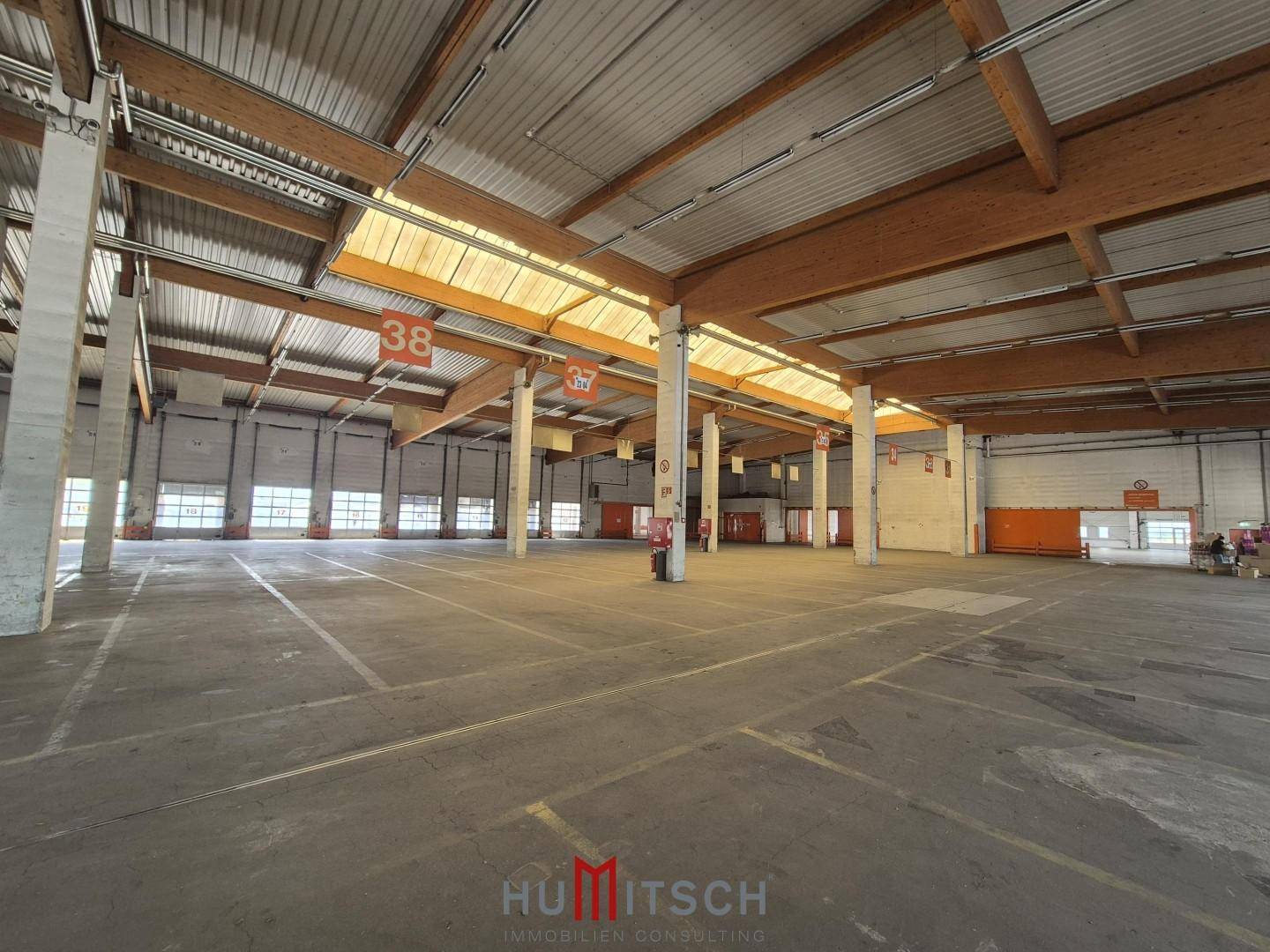 Große Lagerhalle mit vielen Stützpfeilern, Oberlichtern und einer robusten Deckenkonstruktion.