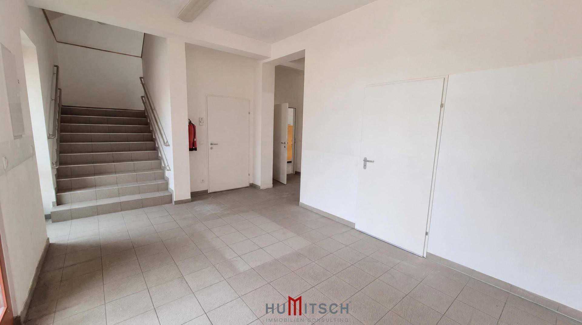 Geräumiger Flur mit Steinfliesenboden und einer Treppe, die in die oberen Stockwerke führt.