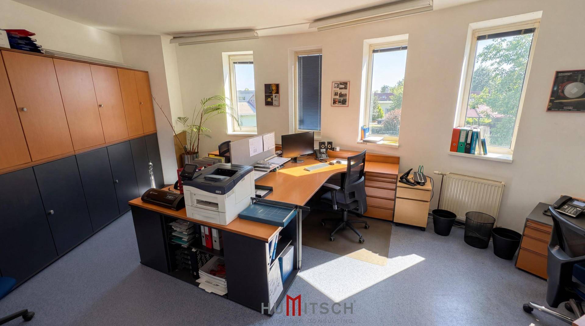 Büro mit Schreibtischen, Stauraum und Fenstern, die viel Sonnenlicht hereinlassen.