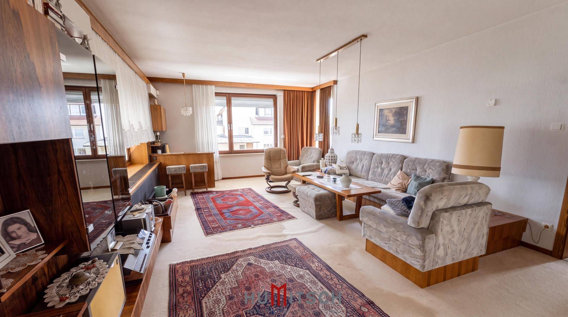 Gemütliches Wohnzimmer mit Teppichboden, Holzvertäfelung und traditionellen Möbeln.
