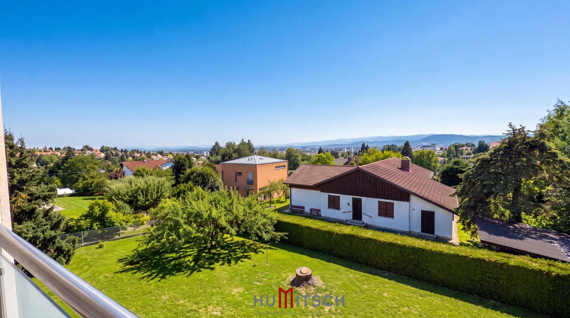 Weitläufiger Ausblick über die umliegende Landschaft mit Häusern und grünen Hügeln.