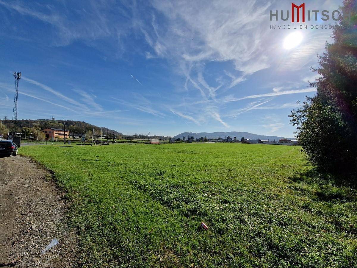 Offenes Feld mit Grasfläche und Blick auf die umliegende Landschaft und Berge.