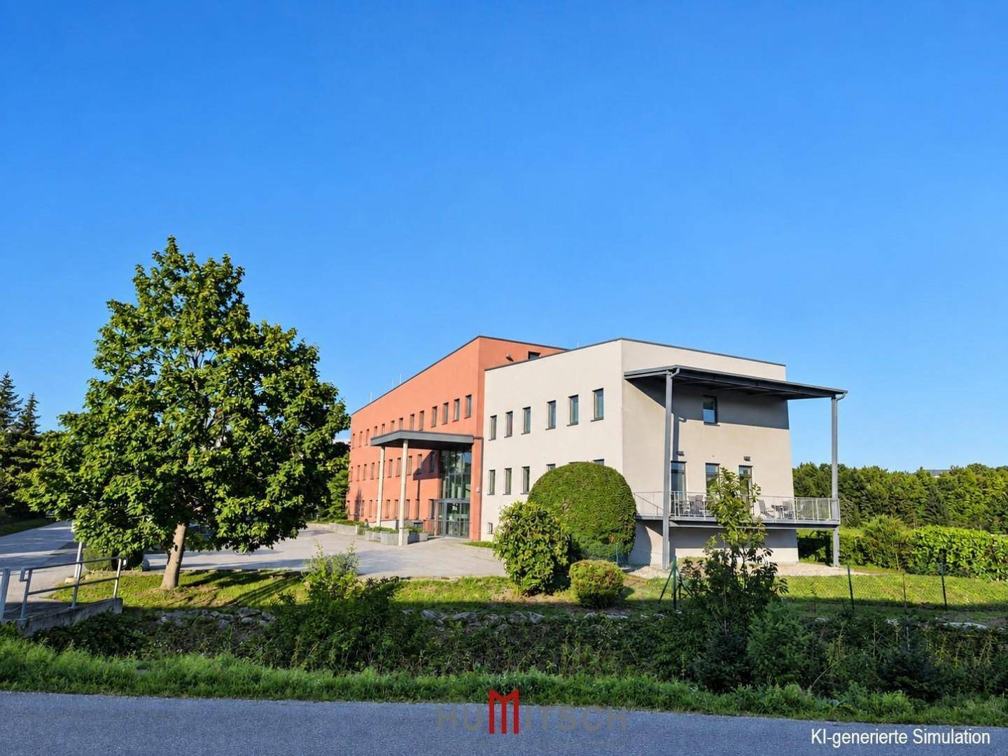 Seitenansicht des Bürogebäudes mit Balkonen und umgebender Natur unter strahlend blauem Himmel.