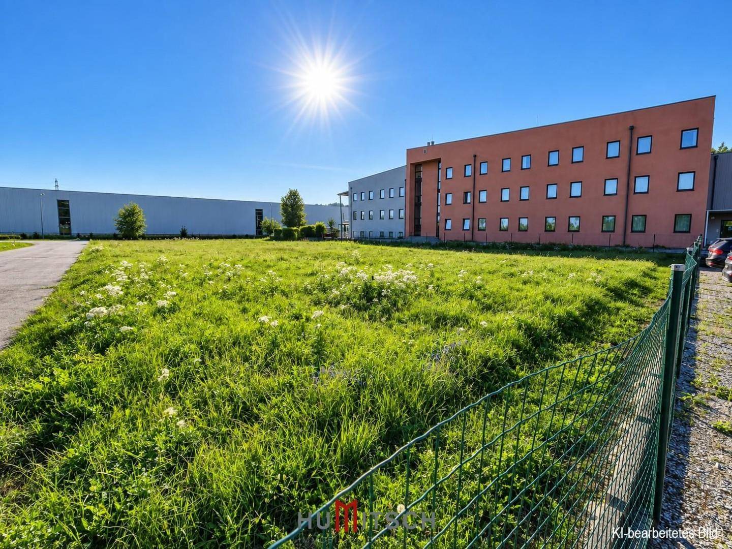 Weitläufige Grünfläche mit blühenden Pflanzen und dem Hauptgebäude im Hintergrund.