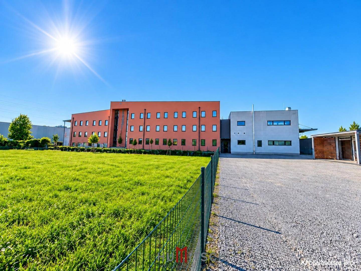 Gesamtansicht des Bürogebäudes mit angrenzender Grünfläche und sonnigem Wetter.