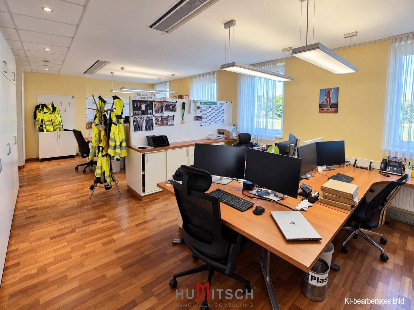 Großraumbüro mit Holzboden, mehreren Arbeitsplätzen und weißen Schränken.