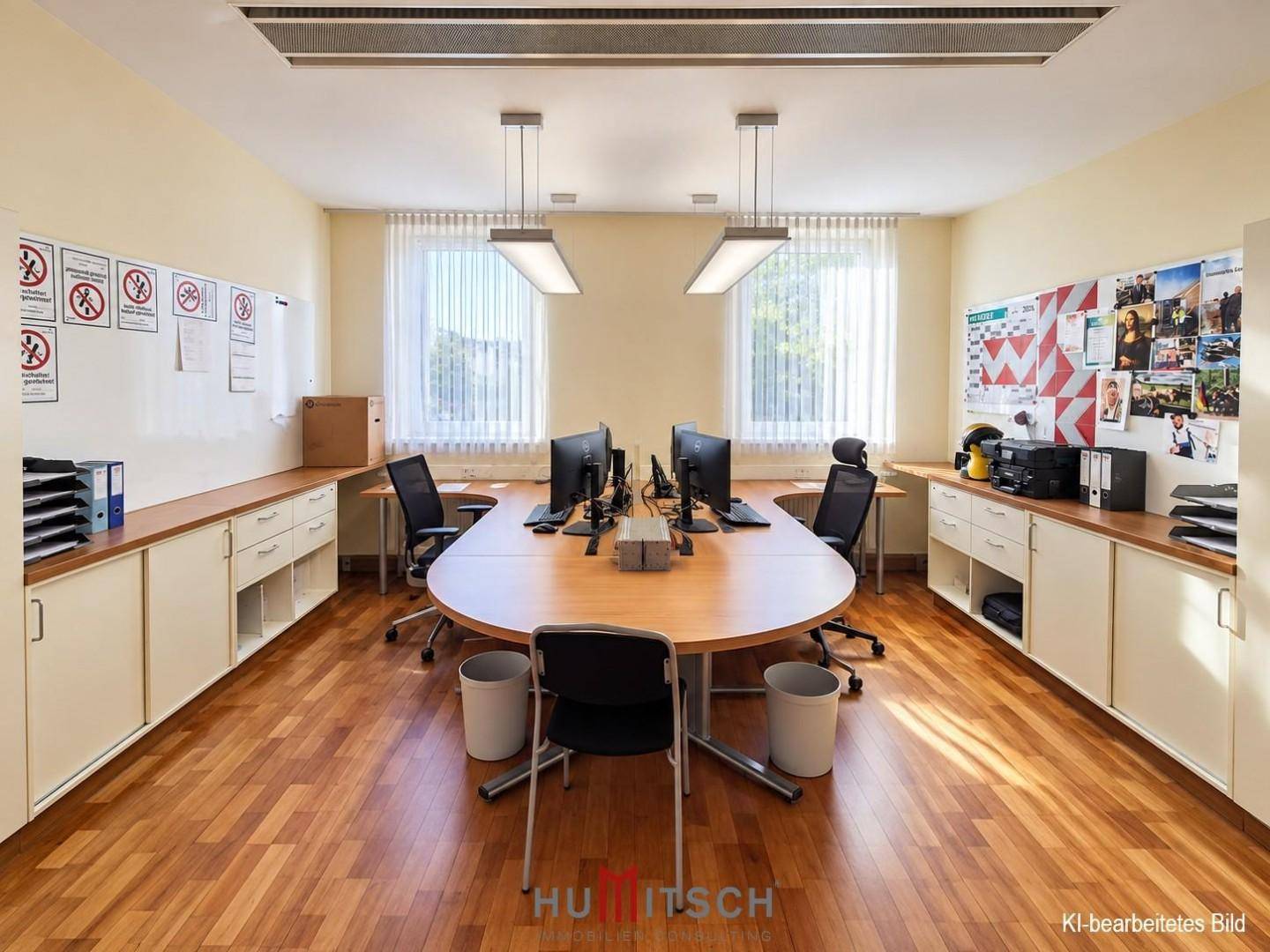 Geräumiges Büro mit mehreren Arbeitsplätzen, Holzfußboden und großen Fenstern für viel Tageslicht.