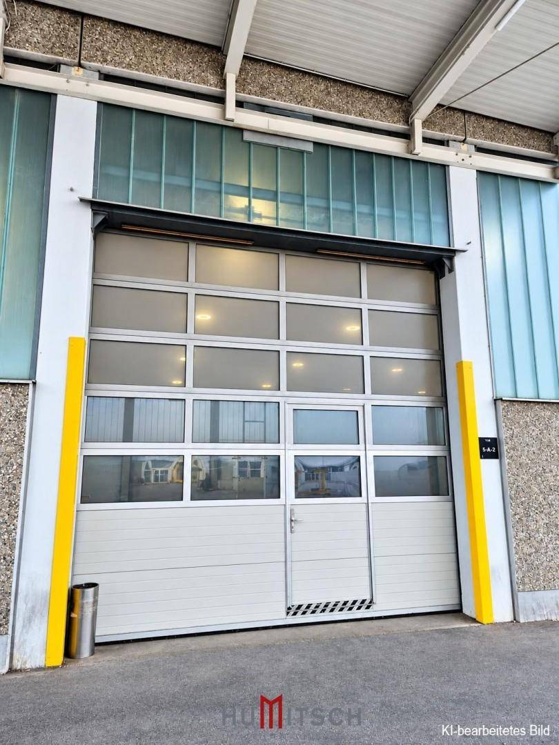 Industrielles Sektionaltor mit vielen Fenstern und integrierter Tür an der Gebäudefassade.