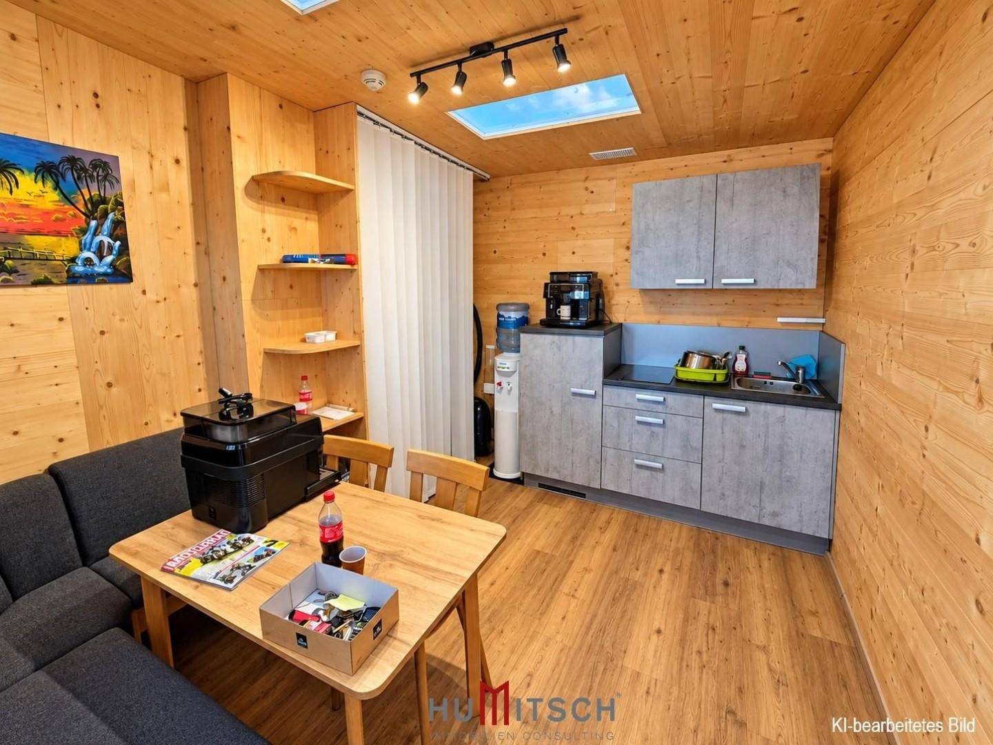 Gemütlicher Aufenthaltsraum mit Holzvertäfelung, kleiner Küchenzeile, Sofa und Esstisch.
