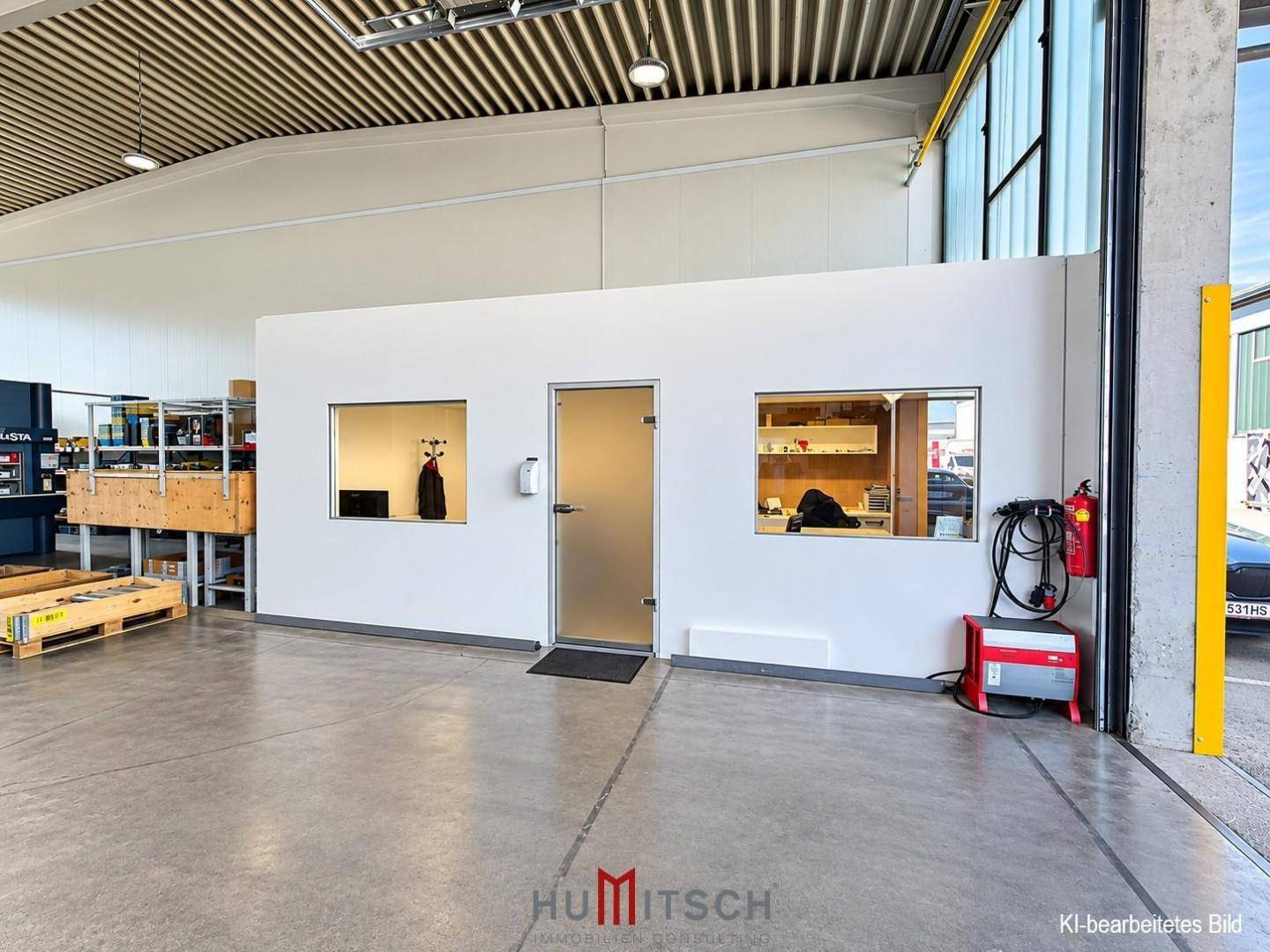 Kleiner, abgetrennter Bürobereich innerhalb einer Lagerhalle mit Fenster und Tür.