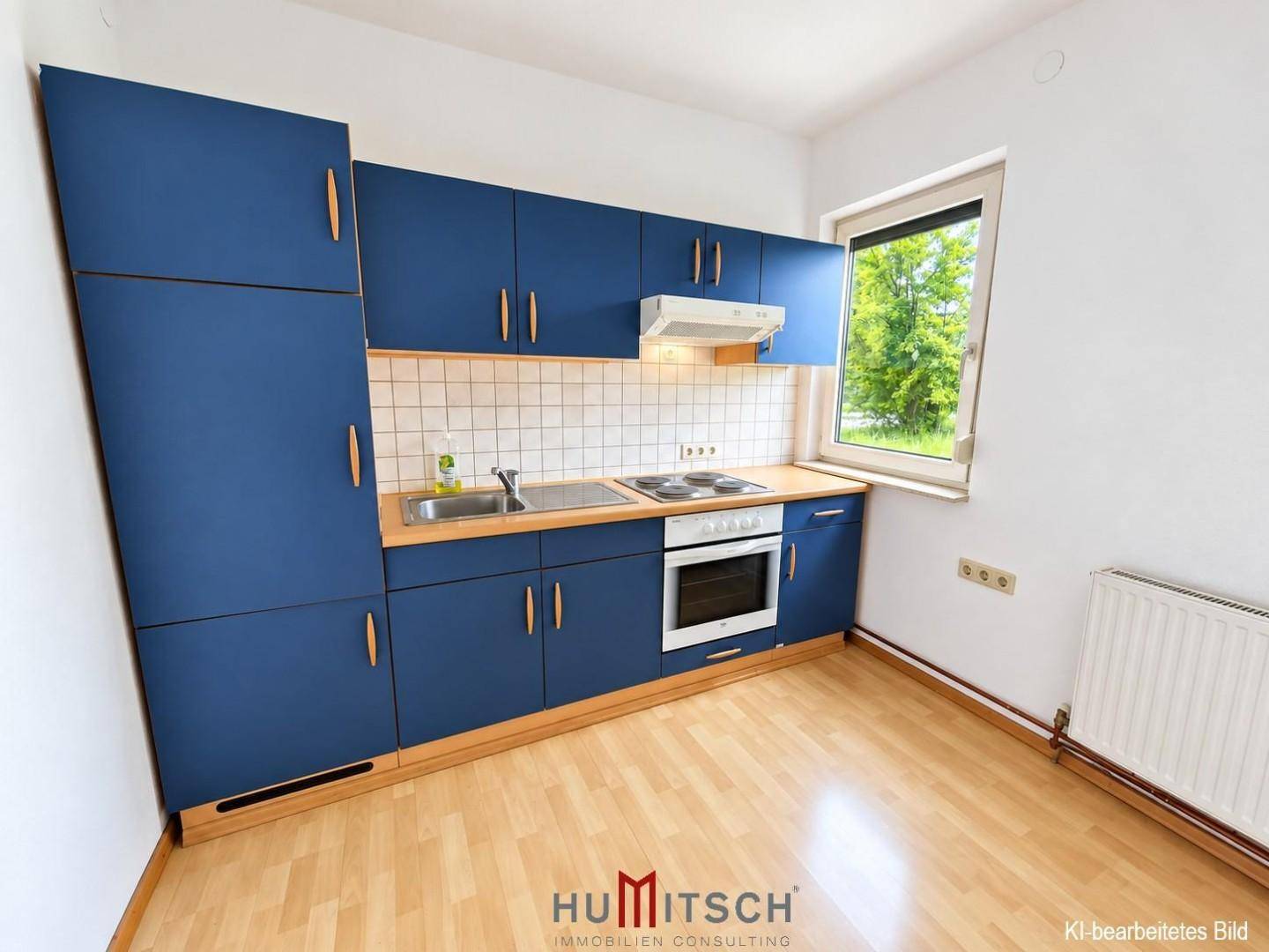 Kleine Küche mit blauen Schränken, weiß gefliestem Fliesenspiegel und einem Fenster.
