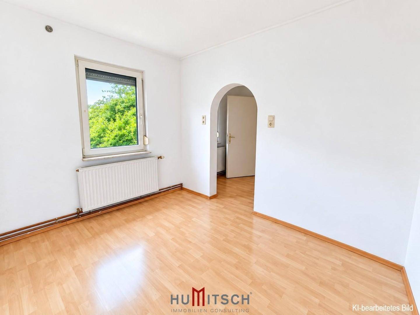 Heller, leerer Raum mit Laminatboden, weiß gestrichenen Wänden und einem Fenster.