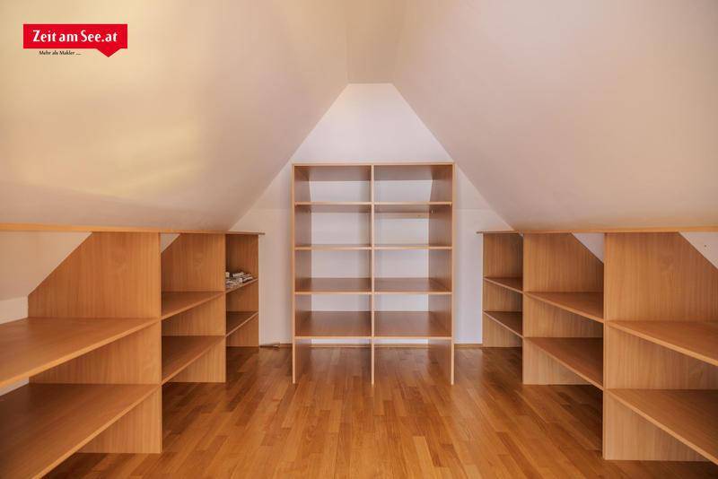 Praktischer Abstellraum im Dachgeschoss mit vielen Holzregalen und Holzboden.
