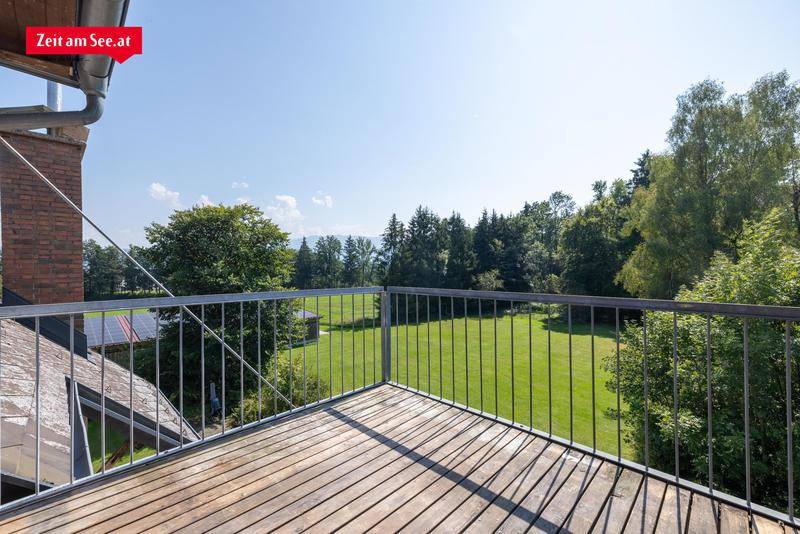 Geräumiger Balkon mit Holzboden und Metallgeländer bietet weiten Blick ins Grüne.