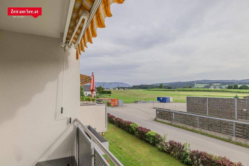 Balkon mit Markise und weitem Blick über grüne Felder und die Landschaft.