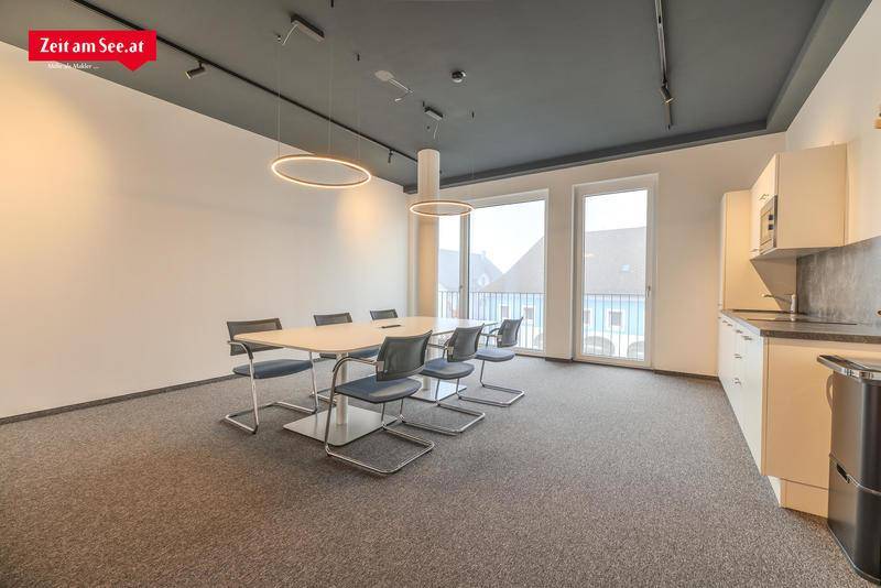 Geräumiger Konferenzraum mit Teppichboden, moderner Beleuchtung und Zugang zu einem Balkon.
