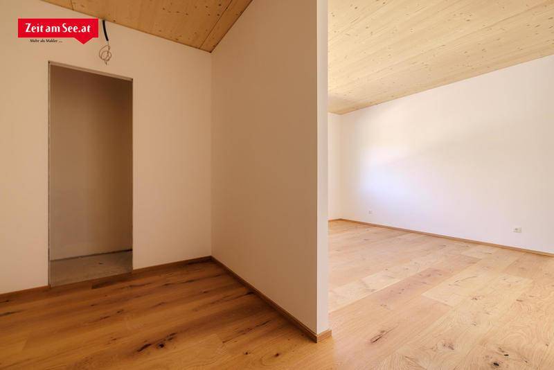 Innenraum mit Holzboden und Holzdecke, der einen Übergangsbereich oder Flur darstellt.