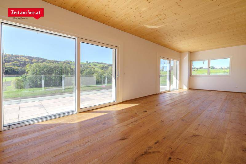 Lichtdurchfluteter Wohnraum mit breiten Holzdielen, Holzdecke und weitem Blick in die Natur.