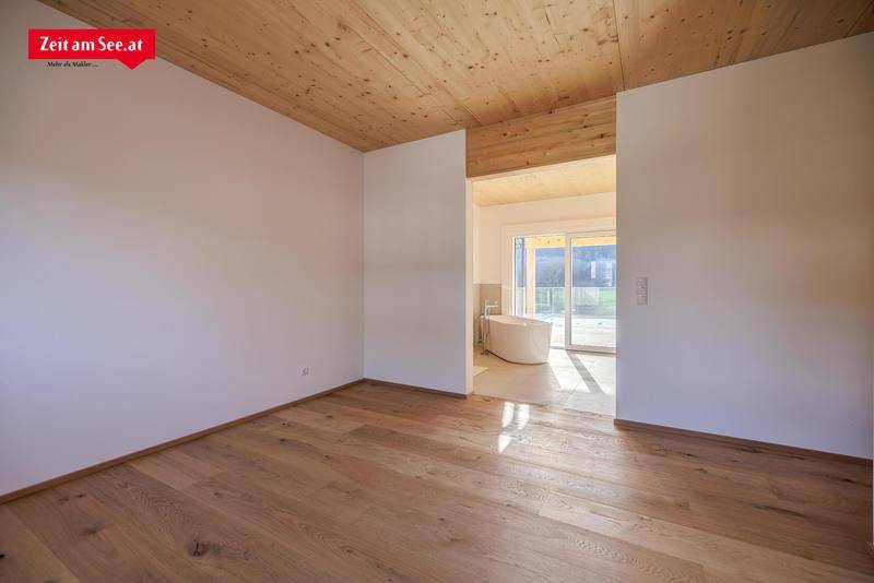 Schlafzimmer mit Holzboden und Holzdecke, das direkt zu einem modernen Badezimmer führt.