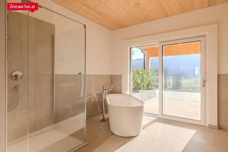 Helles Badezimmer mit freistehender Badewanne, Glasdusche und direktem Zugang zur Außenterrasse.