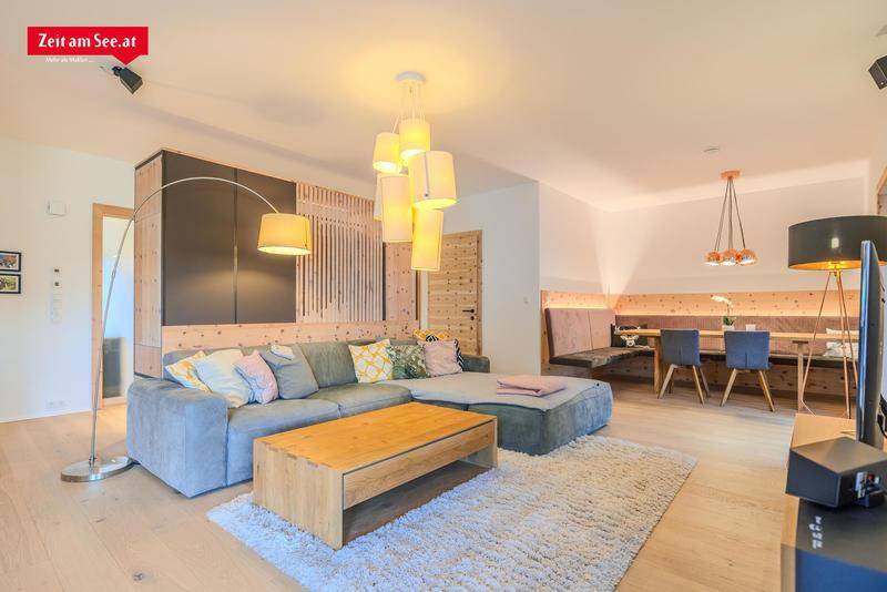 Geräumiger Wohn- und Essbereich mit gemütlichem Sofa, Holzelementen und modernem Lichtdesign.