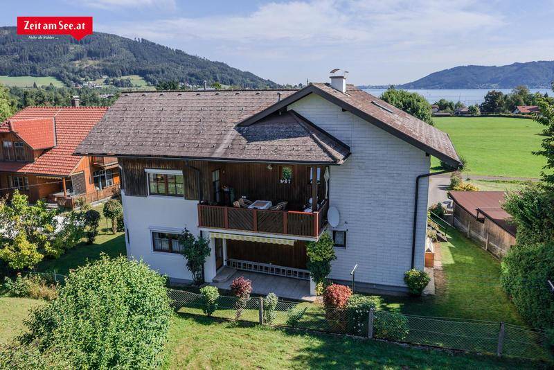 Rückansicht des Hauses mit zwei Balkonen und Blick auf die umliegende Landschaft und den See.