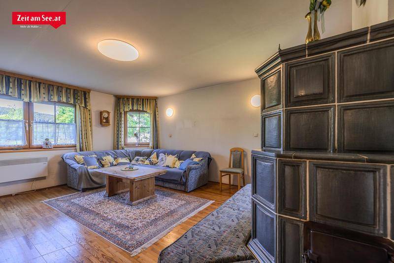 Geräumiges Wohnzimmer mit traditionellem Kachelofen, Holzboden und gemütlicher Sitzecke.
