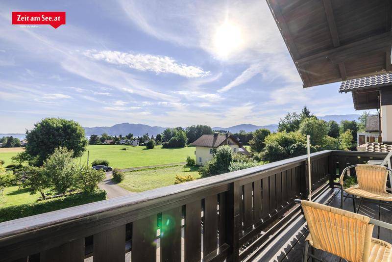 Sonniger Balkon mit Sitzgelegenheiten und Panoramablick auf die Landschaft und den See.