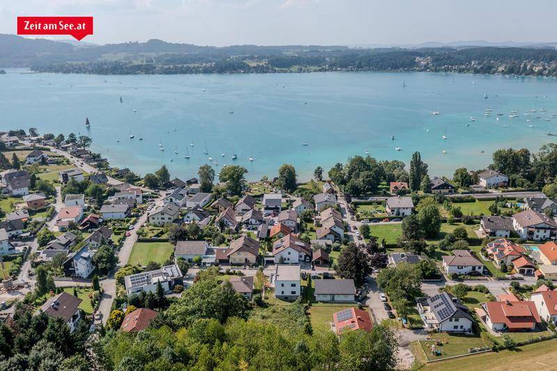 Luftaufnahme einer Wohnsiedlung am Seeufer mit vielen Häusern und grüner Umgebung.