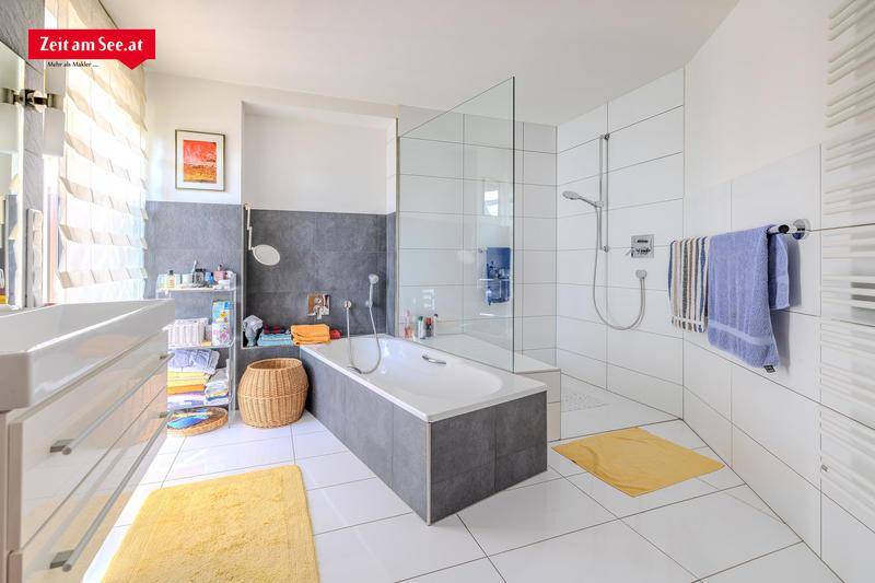 Modernes Badezimmer mit Badewanne, begehbarer Dusche und großen Fliesen.