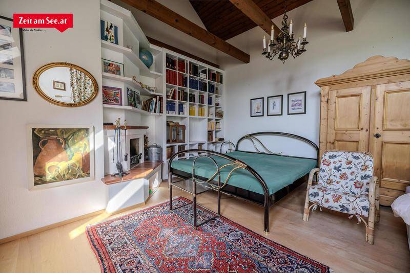 Gemütliches Schlafzimmer mit Holzbalken, integriertem Bücherregal und kleinem Kamin.