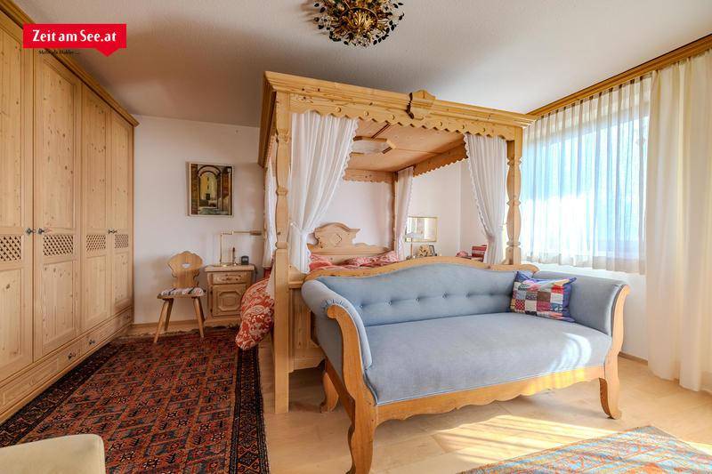 Geräumiges Schlafzimmer mit Himmelbett, Holzschränken und viel Tageslicht.