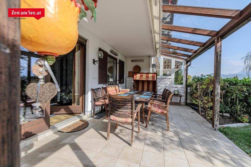 Überdachte Terrasse mit Esstisch und Stühlen, ideal für Mahlzeiten im Freien.