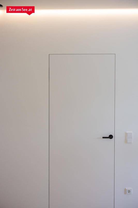 Moderne, minimalistische Tür in einer weißen Wand mit integrierter Beleuchtung.