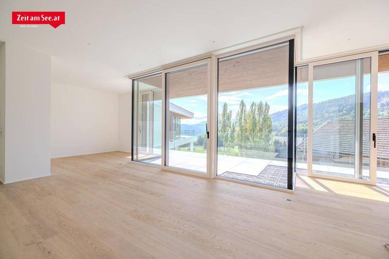 Heller Wohnraum mit Holzboden und raumhohen Fenstern, die einen weiten Ausblick bieten.