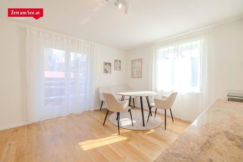 Heller Essbereich mit Holzboden, modernem runden Tisch und Stühlen, sowie großen Fenstern mit viel Tageslicht.