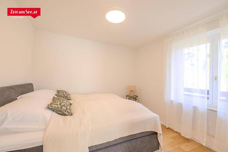 Helles Schlafzimmer mit einem bequemen Doppelbett, Holzboden und einem Fenster, das viel Tageslicht hereinlässt.