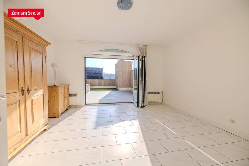Helles Zimmer mit Fliesenboden und breiter Falttür, die zur Terrasse führt.
