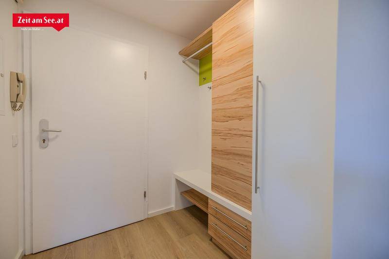 Heller Eingangsbereich mit modernem Einbauschrank, Holzboden und Gegensprechanlage.