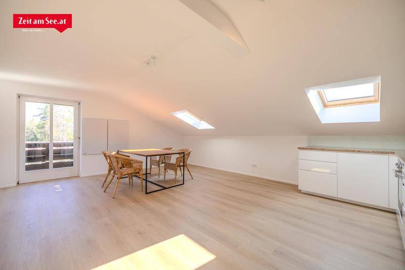 Lichtdurchfluteter Dachgeschossraum mit Esstisch, Holzboden und mehreren Dachfenstern.
